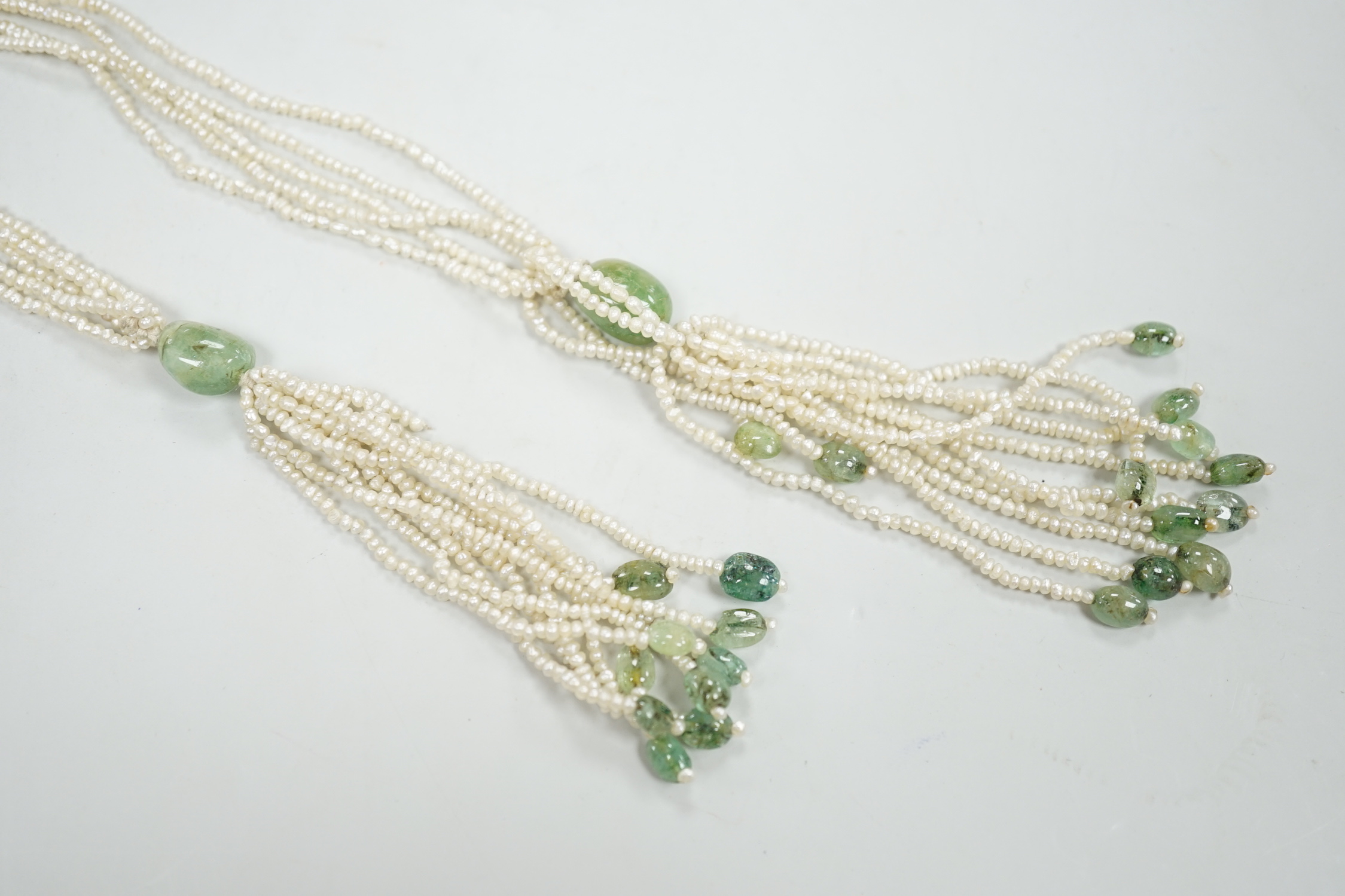 A 19th century Indian multi strand seed pearl and emerald? set long necklace, with gem set tassel drops, 176cm.